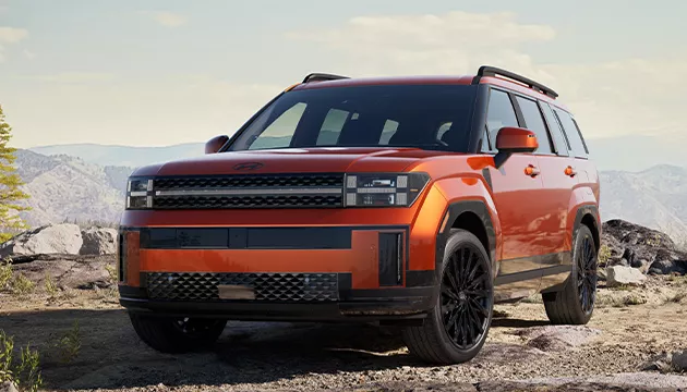 Front view of a orange Hyundai SUV parked on a rocky cliff side