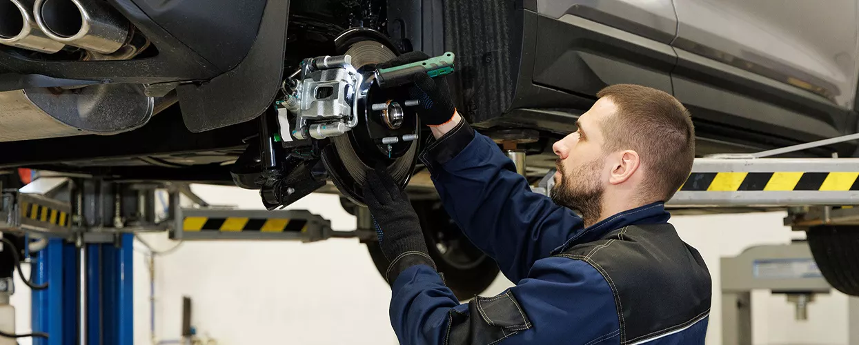 Service mechanic servicing brakes on a vehicle in a service bay