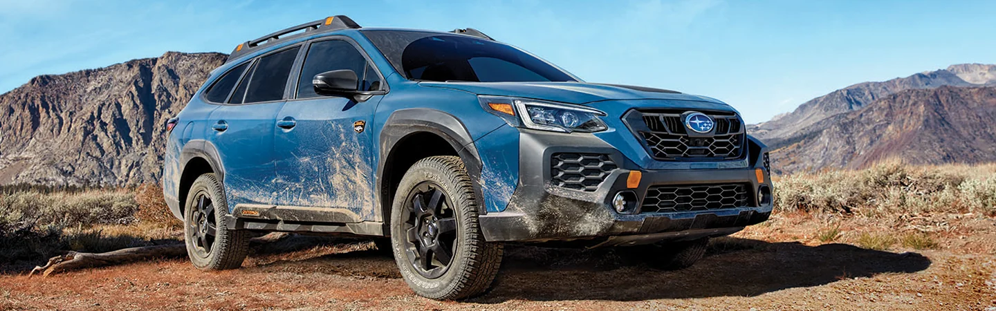 a blue 2025 Subaru Outback Touring looking muddy offroad