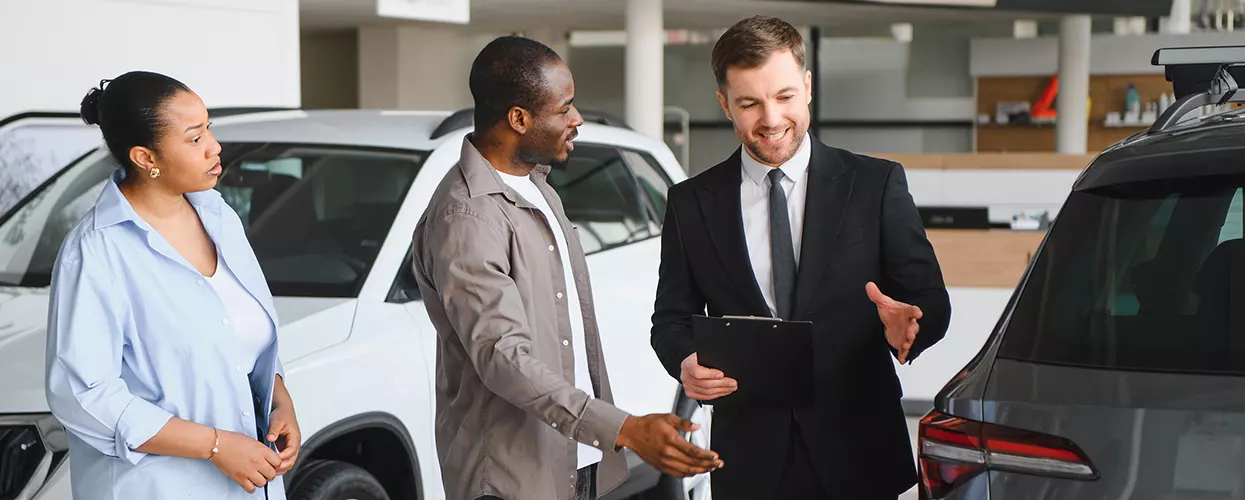 Car dealership sales consultant helping customers compare SUV features and explore vehicle options