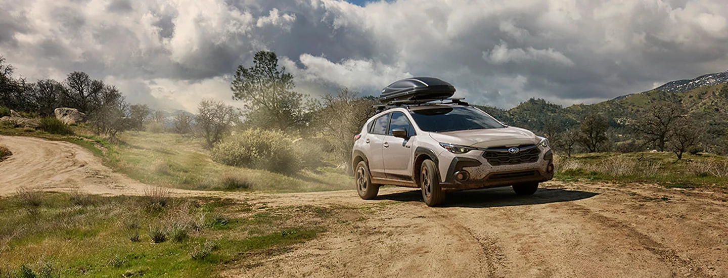 a 2026 Subaru Crosstrek Hybrid with roof racked storage on a dirt road