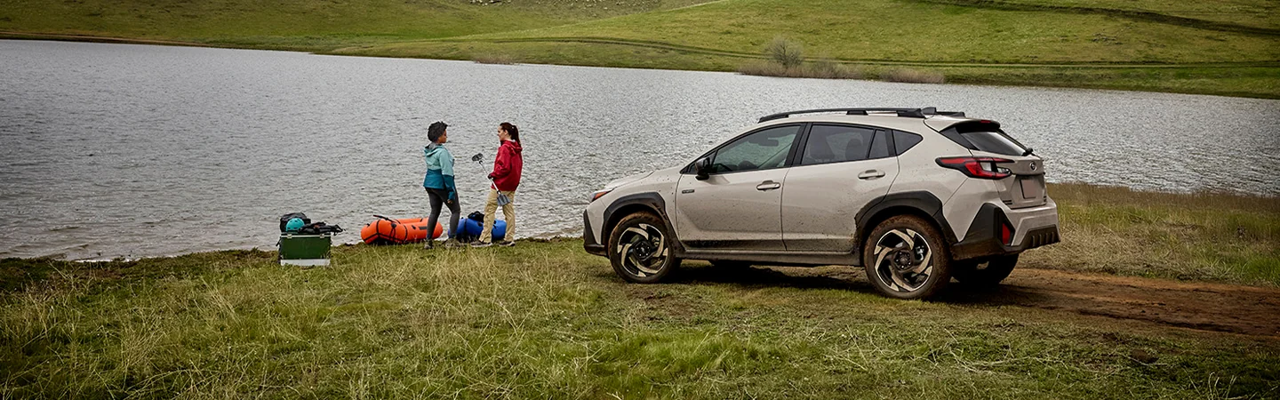 a white 2026 Subaru Crosstrek Sport Hybrid parked by lake with two people nearby