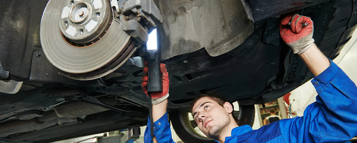 Auto mechnic working on car on a lift in service bay