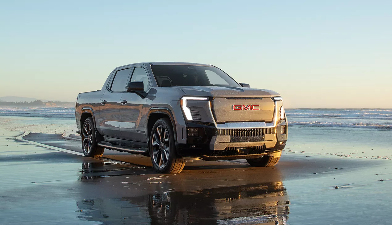 Front view of a EV GMC truck driving down the beach