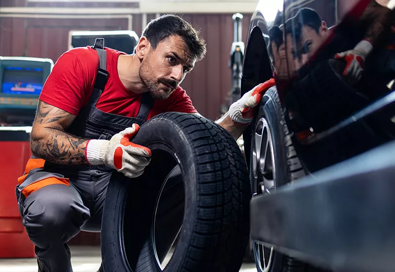 Service tech looking at a tire to change at Crown Buick GMC in St. Petersburg, FL