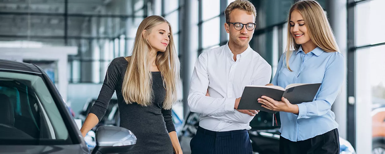 Car salesman showing a customer a booklet in a car dealership