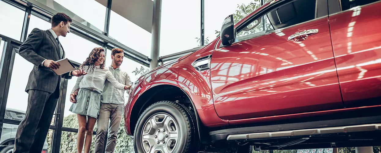 Car salesman showing a couple a new vehicle