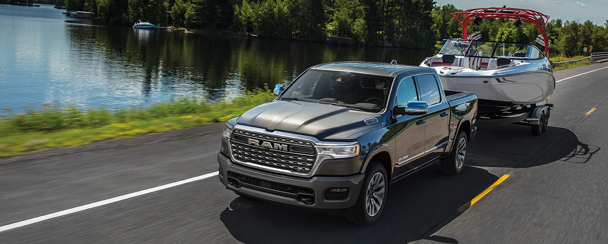 Front view of a gray RAM truck pulling a boat by a lake