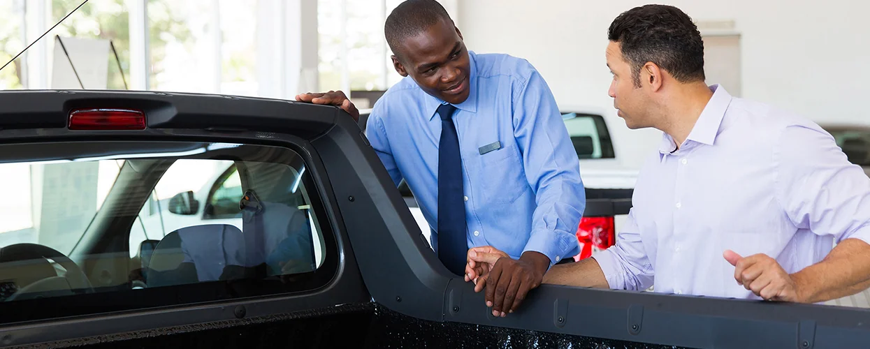 Sales person showing customer the back of a new truck bed
