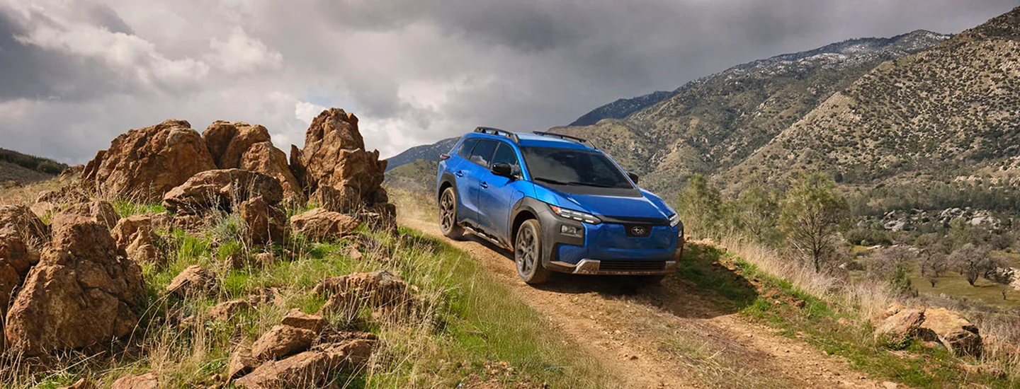 a blue 2026 Subaru Trailseeker driving offroad dirt trail by some rocks