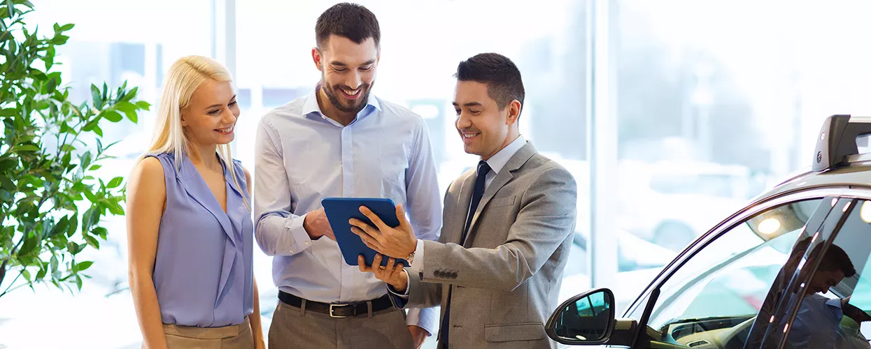 Car salesman showing a couple a tablet