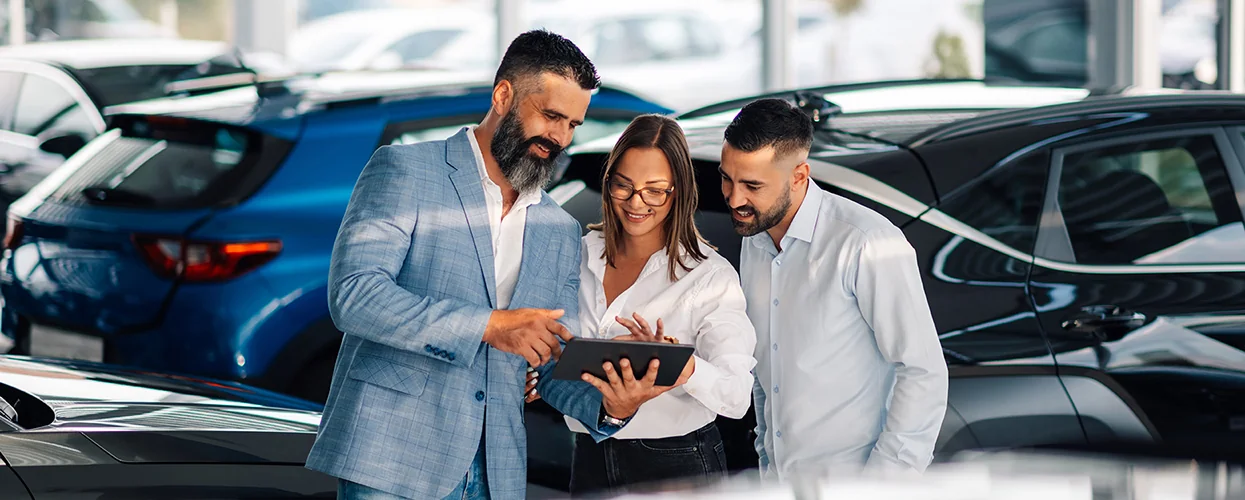 Sales person showing customers specs of a car on a tablet