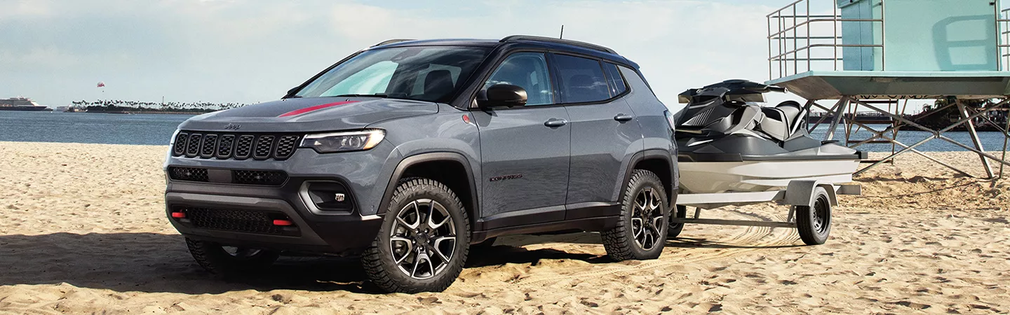 2025 Jeep Compass parked on the beach towing a jet ski