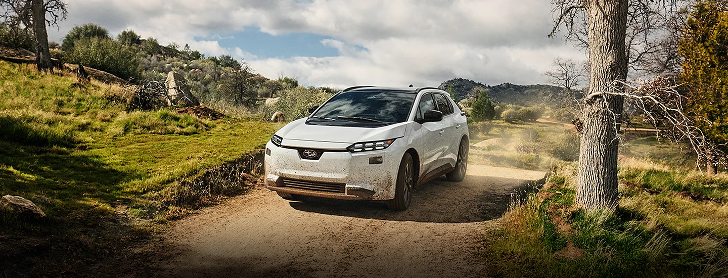 Front view of a white 2026 Subaru Solterra driving on a dirt road