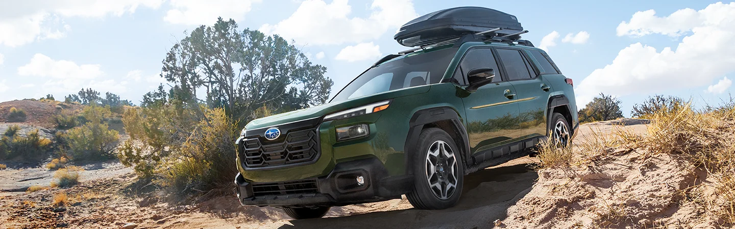 Front view of a green 2026 Subaru Outback Wilderness parked on a hill in the desert