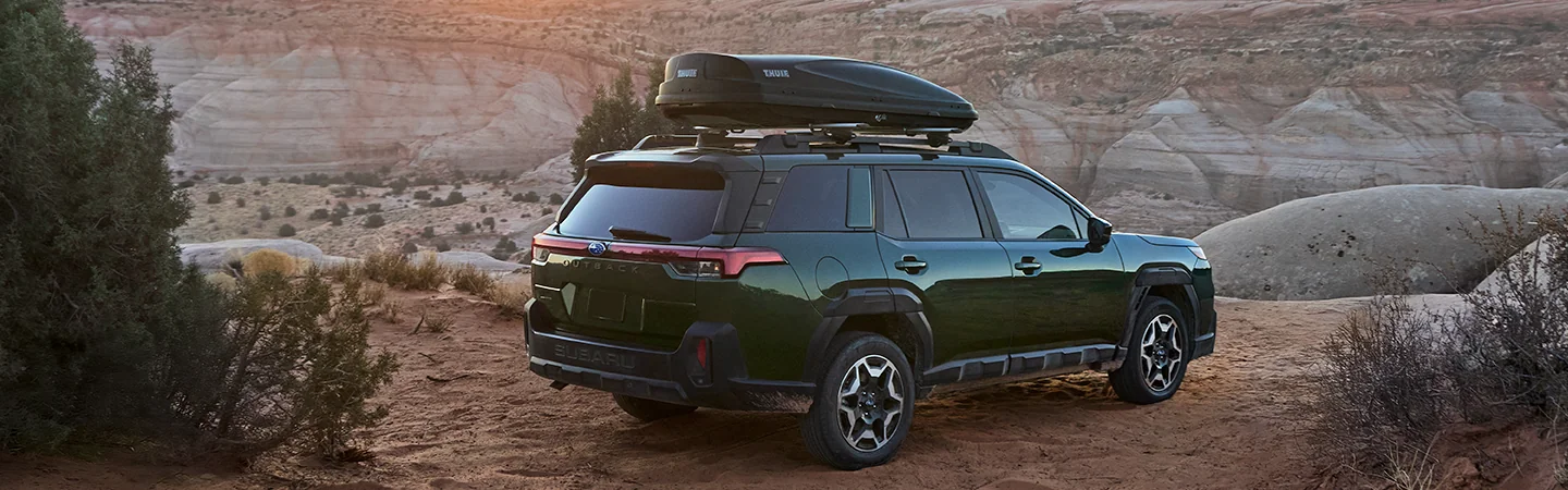 Back side view of a green 2026 Subaru Outback Wilderness parked on a cliff side