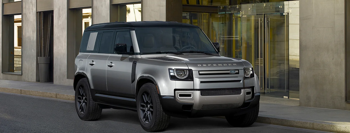 Front view of a parked gray 2025 Defender 110 in front of a building
