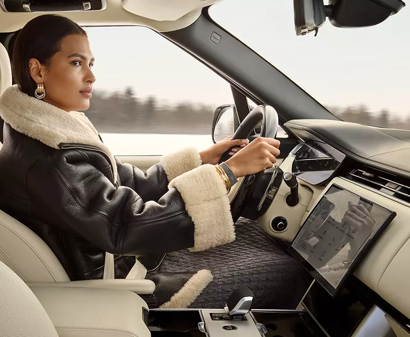 interior of a 2027 Range Rover with driver at wheel showing the front seating area
