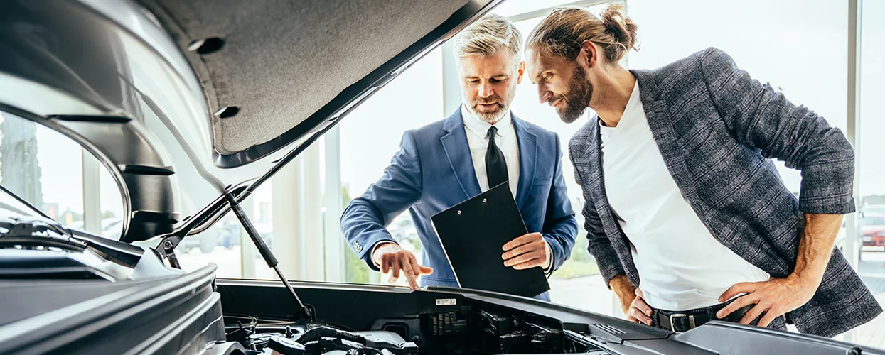 Sales person showing customer under the hood of a new Volkswagen