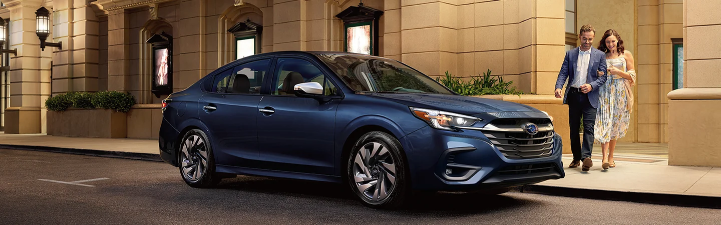 blue 2025 Subaru Legacy Touring XT parked in city with couple walking nearby