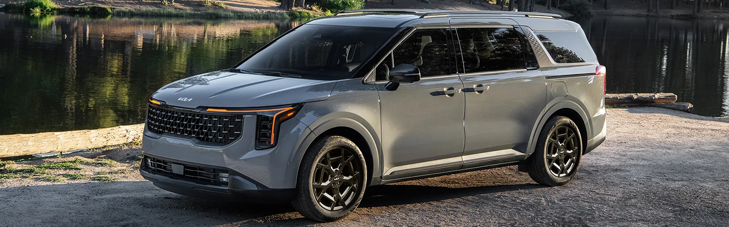 front view of a 2025 Kia Carnival MPV Hybrid LXS paked by lake