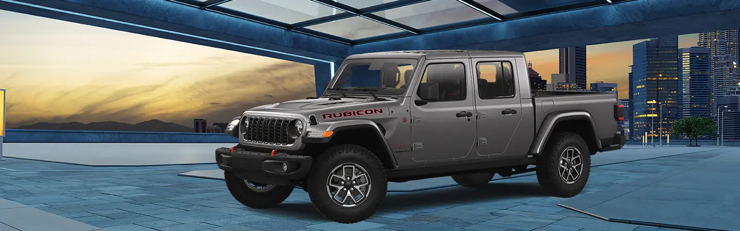 A gray 2025 Jeep Gladiator parked iwht a city in the background