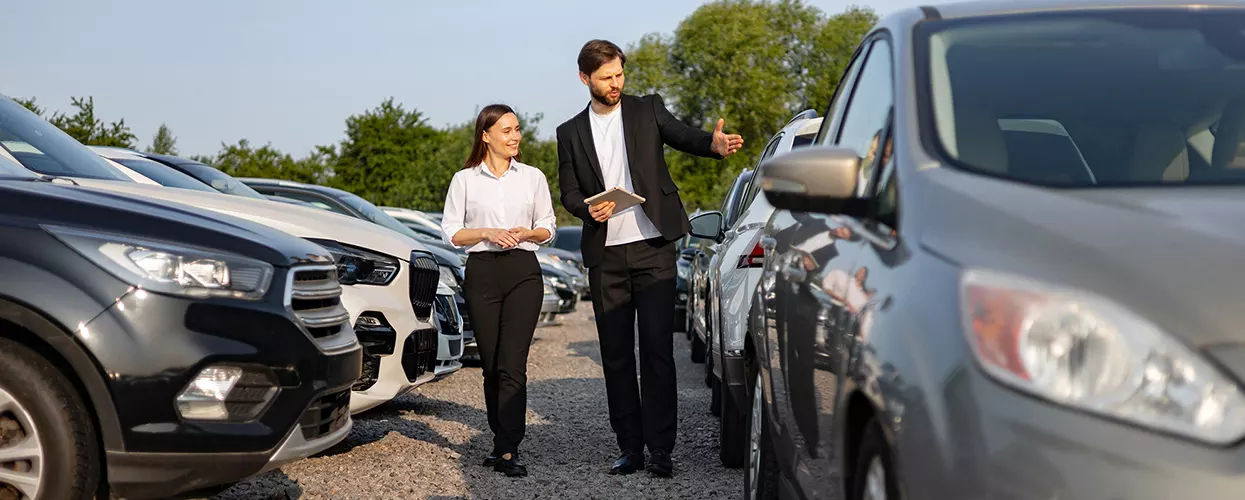 Sales person walking the dealership lot with a customer