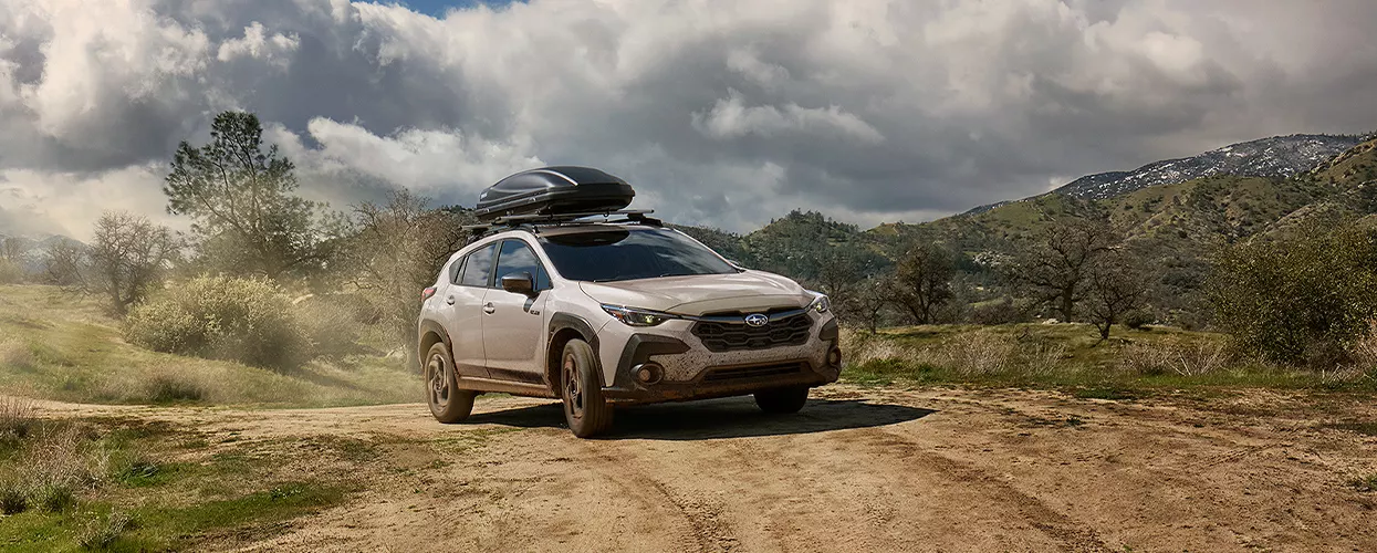 Subaru Outback driving down a dirt road