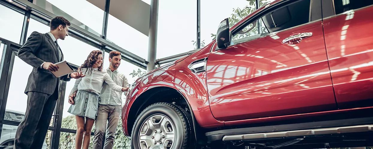 Car salesman talking to a couple about a new vehicle