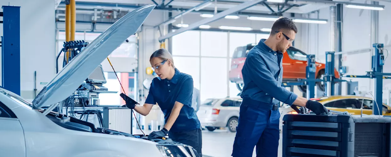 Two service mechanics working under the hood of a vehicle
