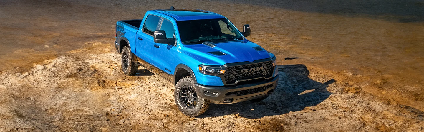 Front view of a parked blue 2026 RAM 1500 on a rocky sea shore