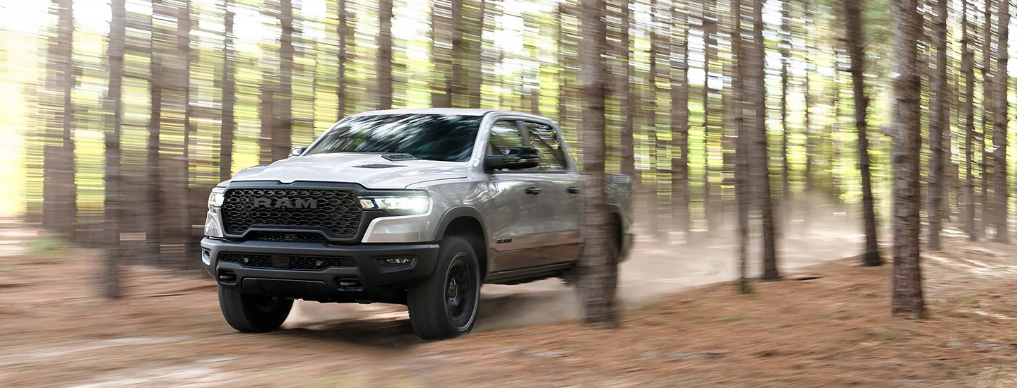 2026 RAM 1500 driving through the woods with trees around
