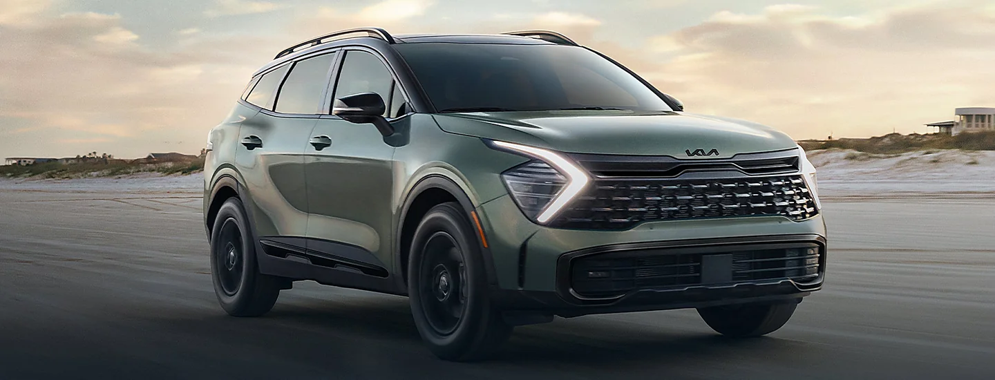 Front view of a 2025 Kia Sportage driving on the beach