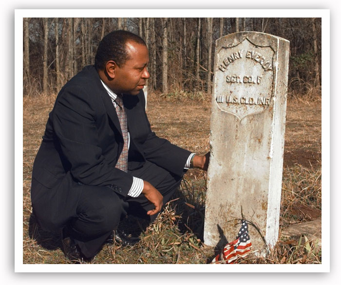 Currie Ballard kneels beside a tombstone in Langston's Beulahland Cemetery in February 1999.