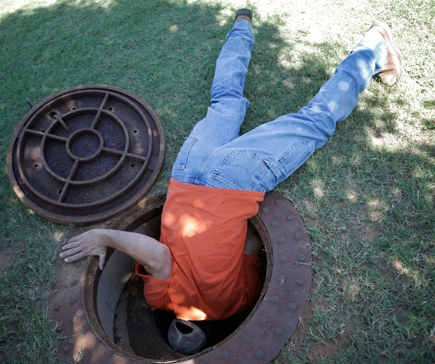 Street superintendent Tenny Maker looks in a manhole in Guthrie.