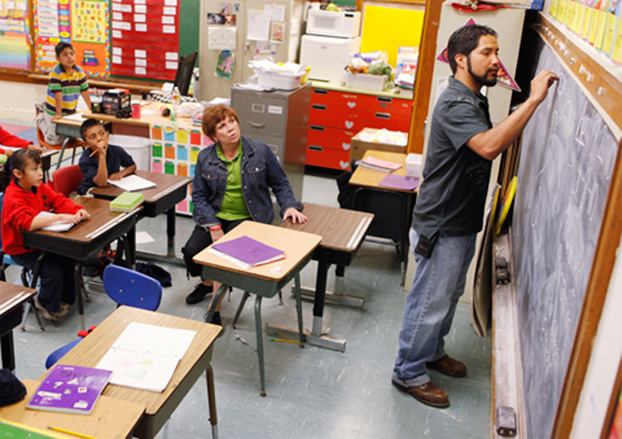 Miguel  Rayos, 22, draws a picture for students at Shidler Elementary while his mentor, Sally Goin looks on. Goin, a retired Edmond school teacher, helped Rayos learn to read. Photo by Paul Hellstern, The Oklahoman