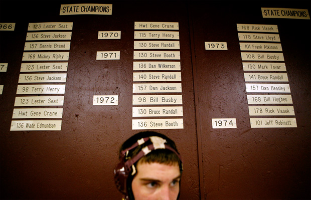 Hayden Workman stands under a list of former Perry champions. Current wrestlers know the school’s tradition well and strive to add another layer to it during their careers. 