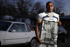 Quintaz Struble holds a photo of his father Mandrell Dean in front of Dean's 1986 Cutlass Supreme, which now belongs to Quintaz. The photo, which hangs on Struble's bedroom wall, shows Dean dunking in a junior high basketball game.