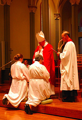 Ordinands kneel on the steps in the cathedral sanctuary as bishop prays