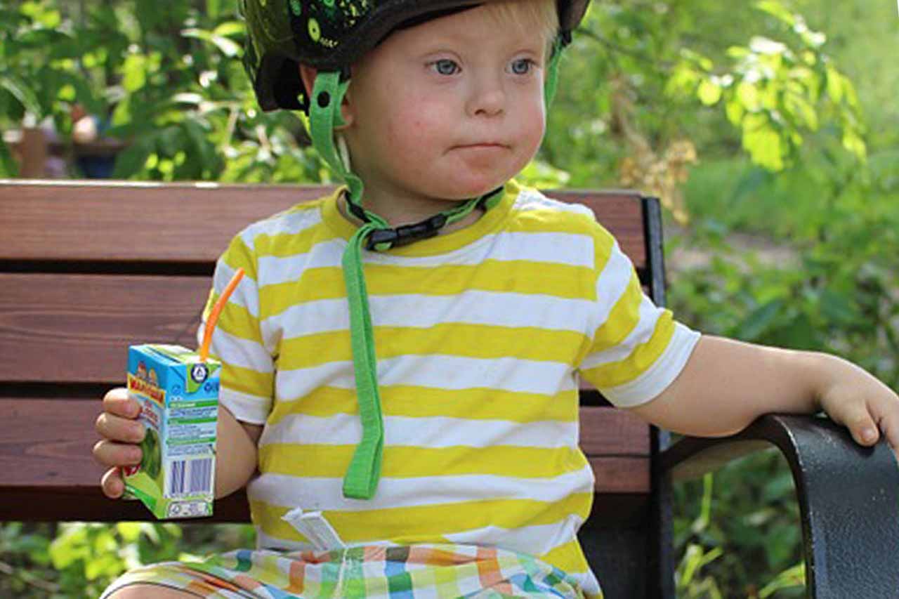 boy with down syndrome and juice drink