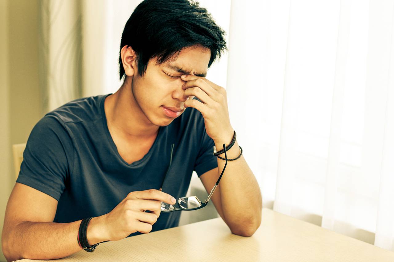 Young man with eyeglasses suffering from dry eyes