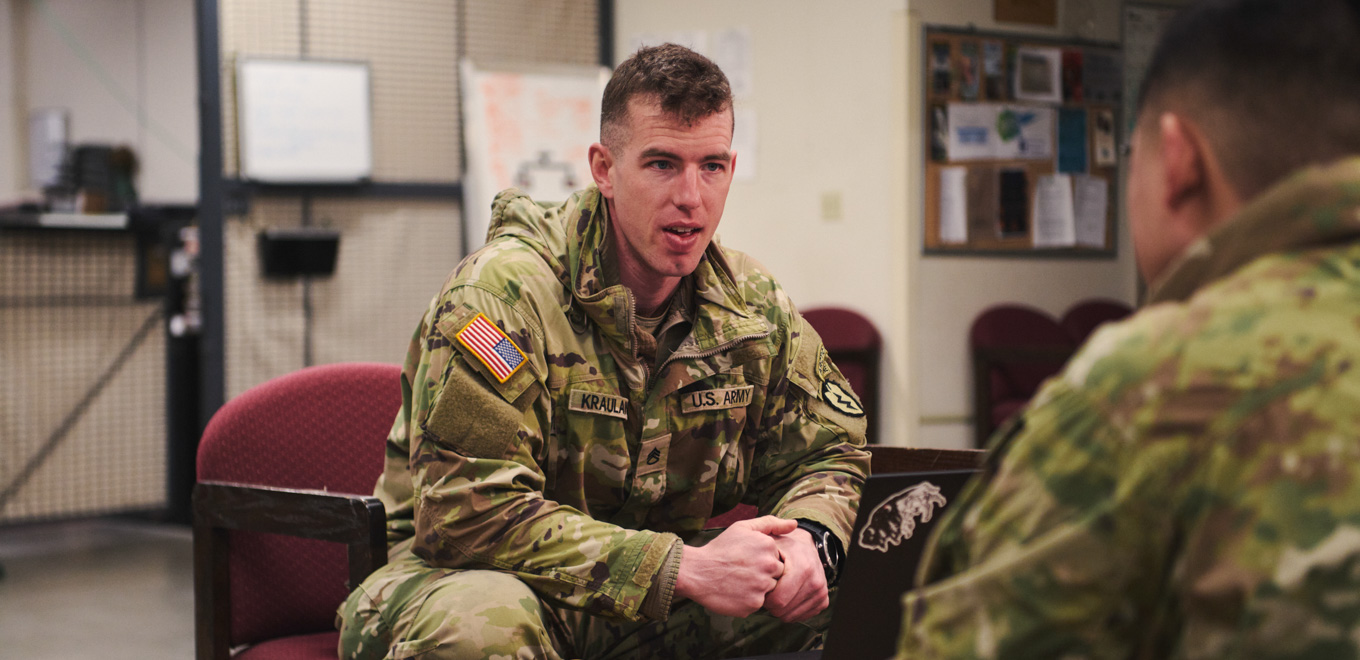 adam sits and talks to fellow soldier