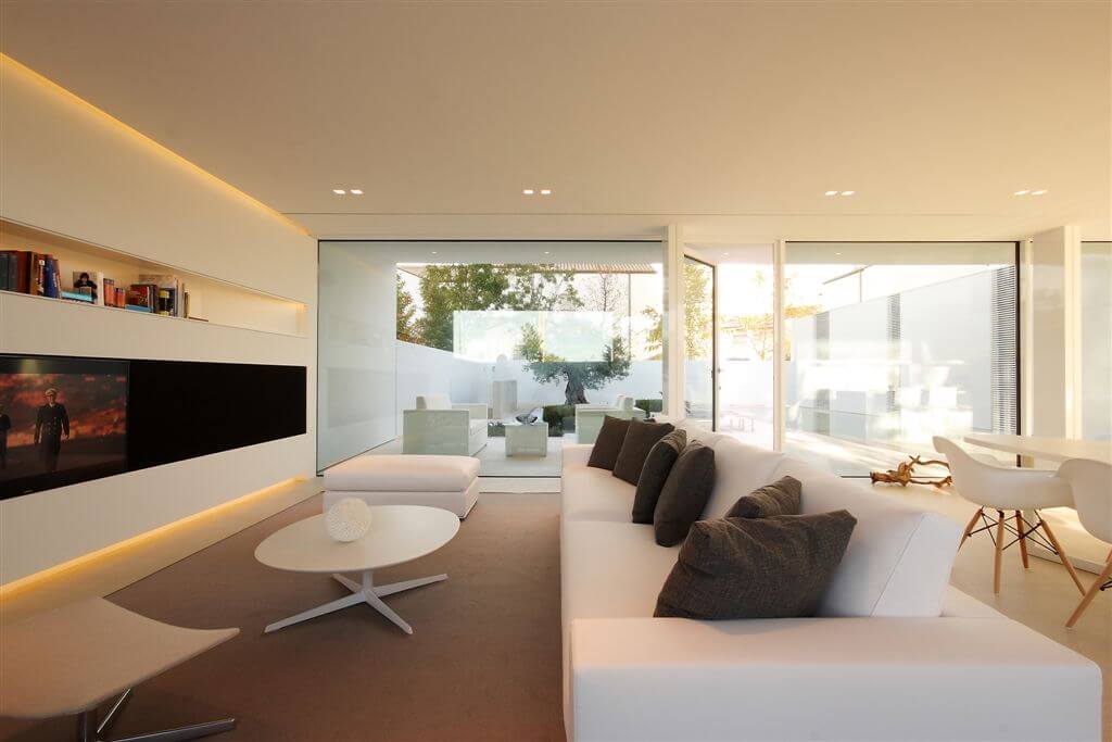Side angle of living room with view to pool and patio area, white extra-long couch and ottoman, and dining area on the side. Side angle of living room with view to pool and patio area, white extra-long couch and ottoman, and dining area on the side.