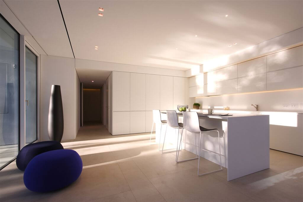 Alternate view of kitchen area featuring minimalist cupboards, island, and hidden recessed lighting. Alternate view of kitchen area featuring minimalist cupboards, island, and hidden recessed lighting.