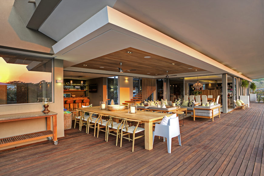 We begin just outside the home on the extensive rear patio, awash in rich natural wood panels. Here, the outdoors blends with the interior in a large dining and relaxing space.