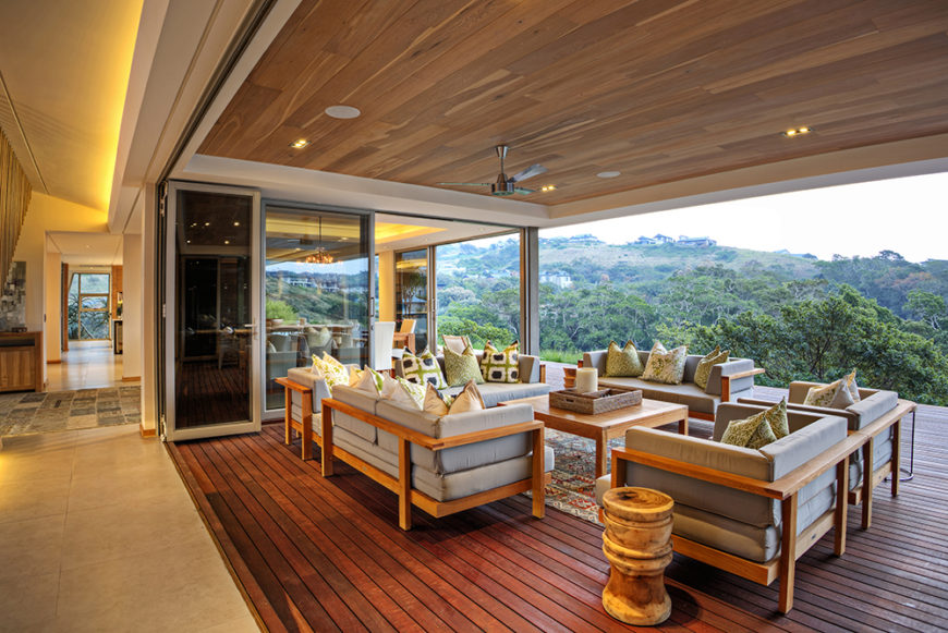 With the folding glass panels fully retracted, the interior meshes perfectly with this outdoors space, protected from the elements by a large overhang and filled with comfortable furniture.