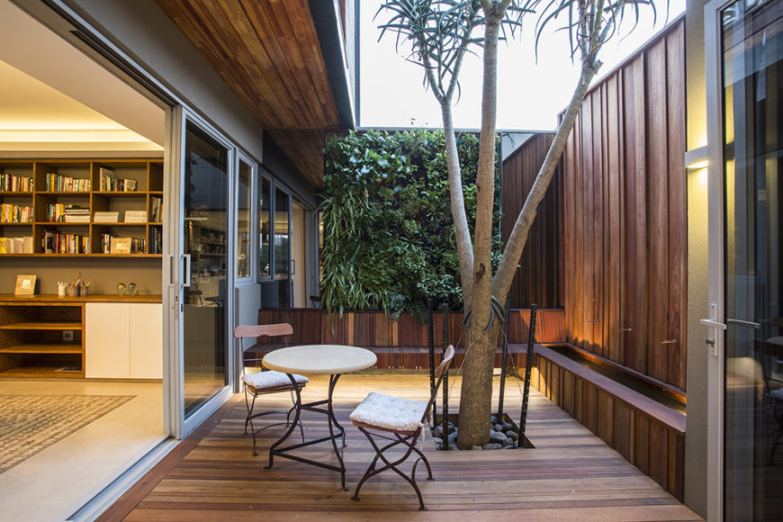 Many rooms throughout the home connect directly to the deck, including this cozy, private space with a tree growing through it. Glass panels and large door openings blur the lines between indoors and out.