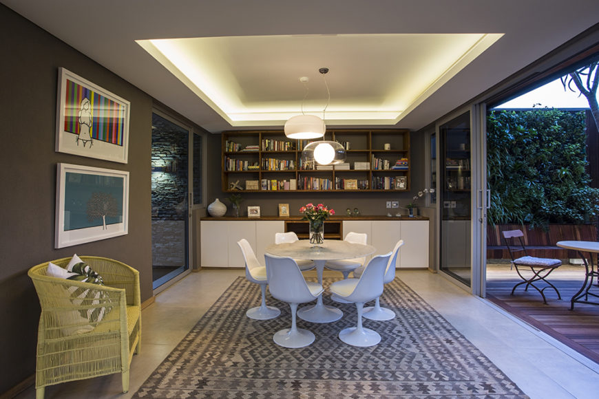 Here's the cozy dining space just inside from the patio seen above. The room is flush with artwork, shelving, and innovative lighting tucked into the raised ceiling.