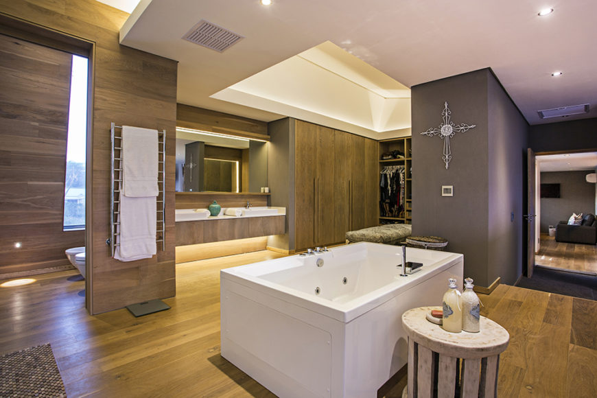 The bedroom boasts a completely open bathroom design, with a large jacuzzi tub at center. The room also houses the full vanity, toilet area, and an extensive closet space.