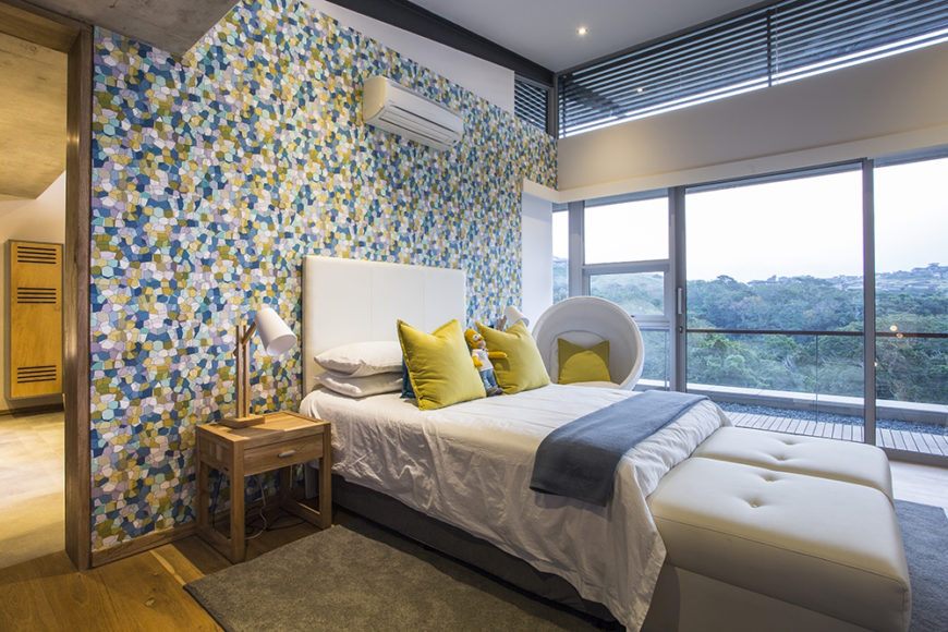Here's a secondary bedroom, awash in bright colors thanks to a patterned feature wall. To the right, we can see the full height glass sliding panels that allow for breathtaking views and direct balcony access.